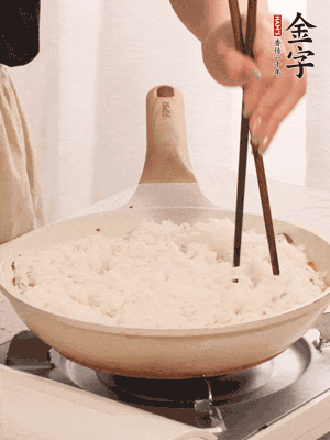 把瀝干水分的米飯均勻鋪在上面，筷子戳幾個(gè)洞，以便透氣，轉(zhuǎn)小火蓋上蓋子燜至水分收干，大概10分鐘。